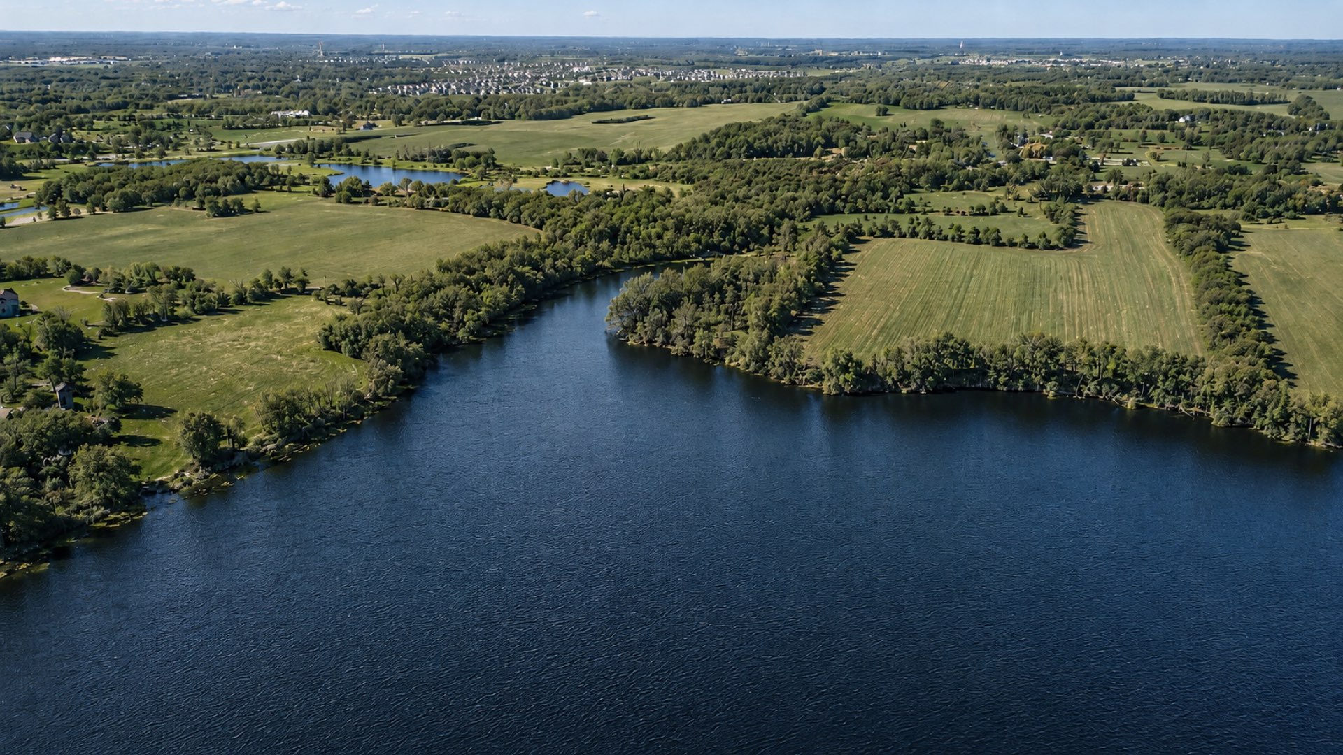 Aerial view over the lake, fields, and woods around the Legacy Woods homesites in Dayton, Minnesota